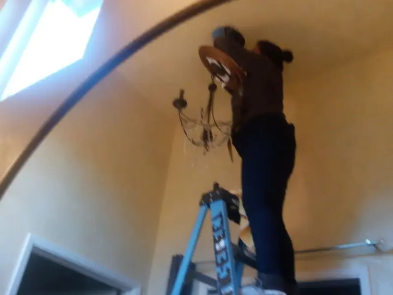 Electrician installing a chandelier in a Belleville residence